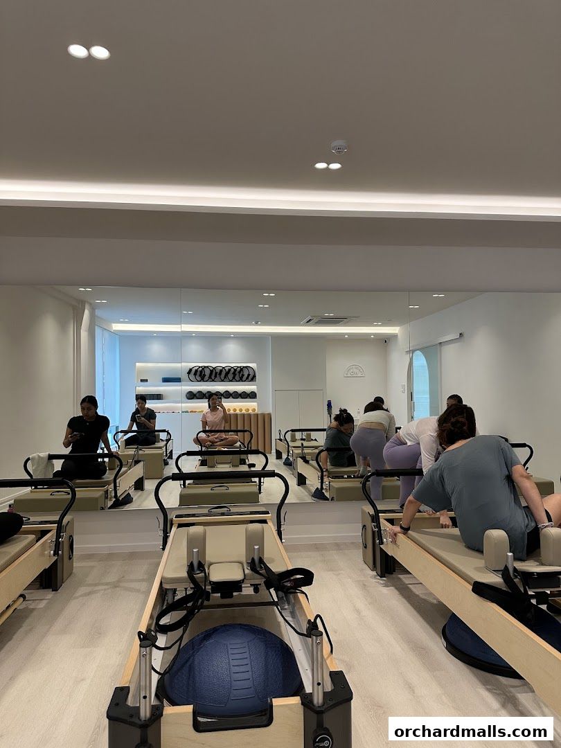 People practicing Pilates on reformers in a bright, mirrored studio.