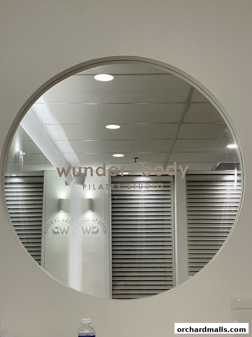 A circular mirror reflects the 'Wunderbody Pilates Studio' sign and interior.
