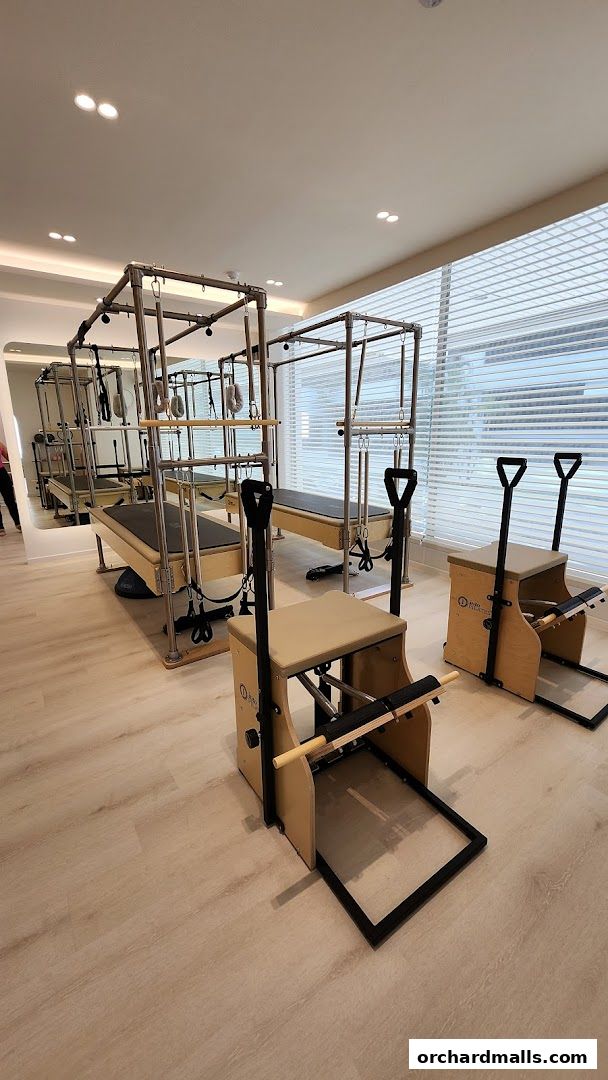 Interior of a modern Pilates studio with reformers and chairs.