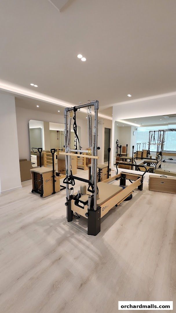 Interior of a modern Pilates studio with reformers and other equipment.