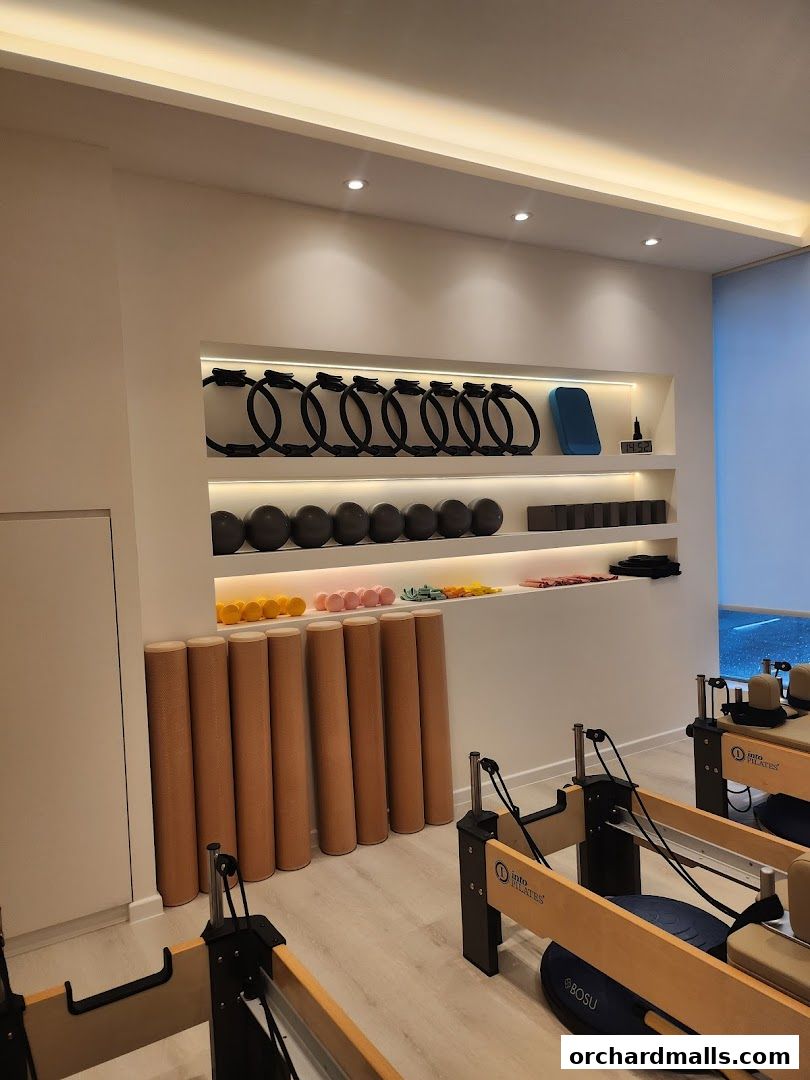 Interior of a modern Pilates studio with reformers, foam rollers, and exercise equipment.