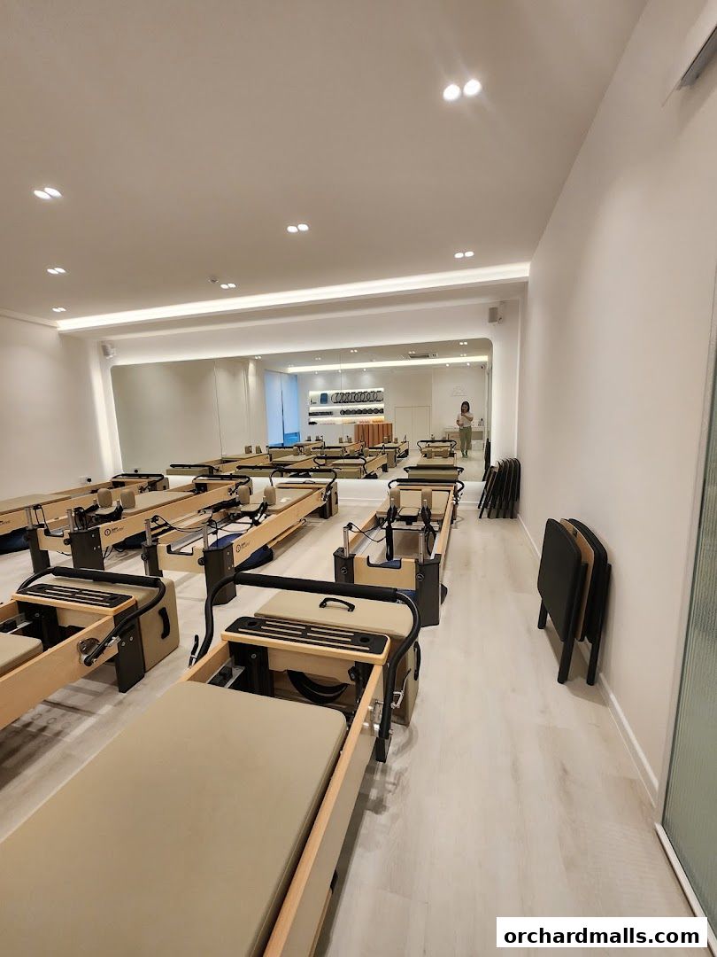 Interior of a modern Pilates studio with multiple reformers and a mirrored wall.