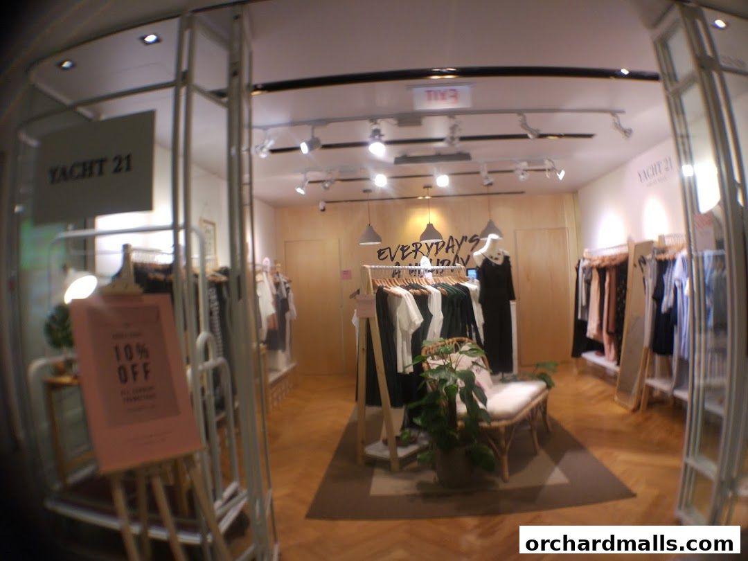 Interior view of a clothing store with racks of apparel and a display sign.