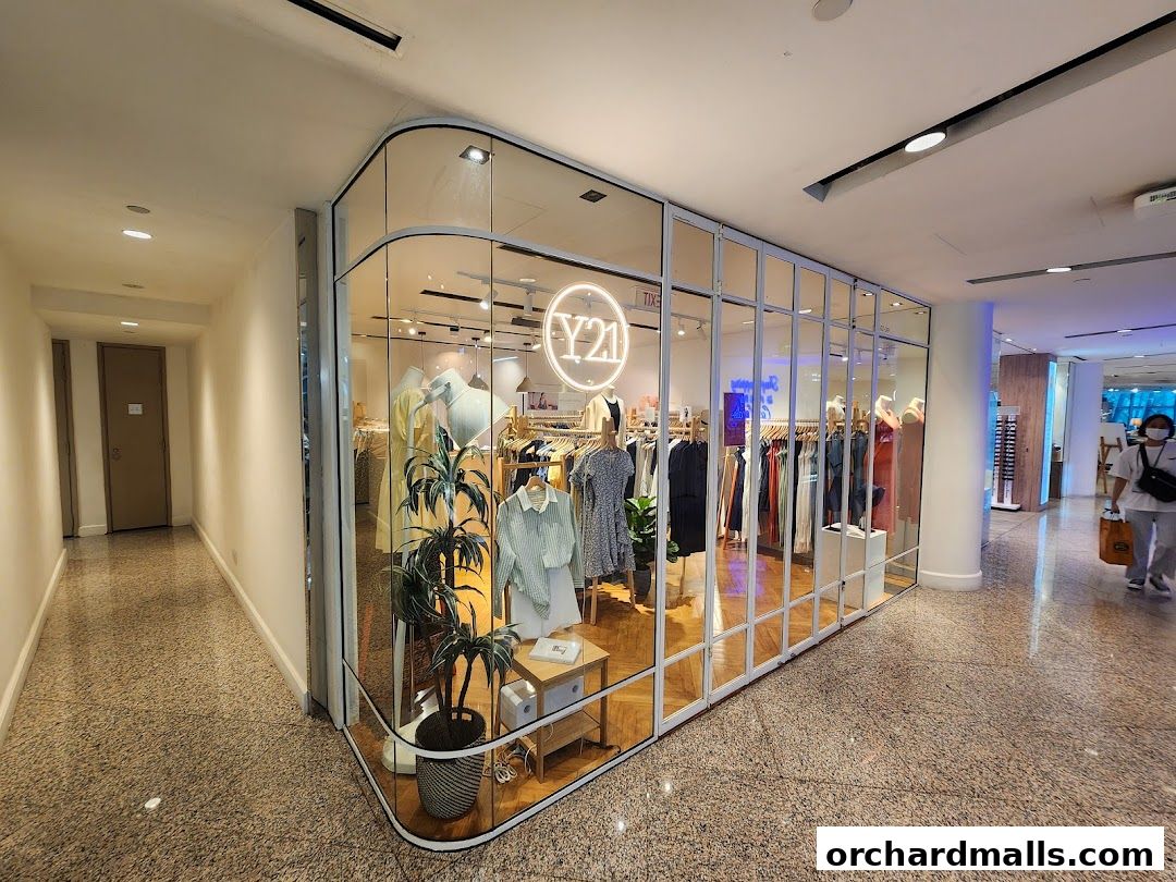 A modern clothing store with a glass facade displaying mannequins and apparel.