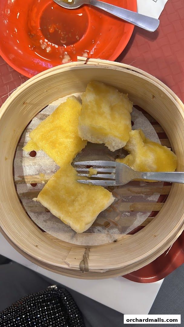 A close-up of kaya toast served in a bamboo steamer with a fork.