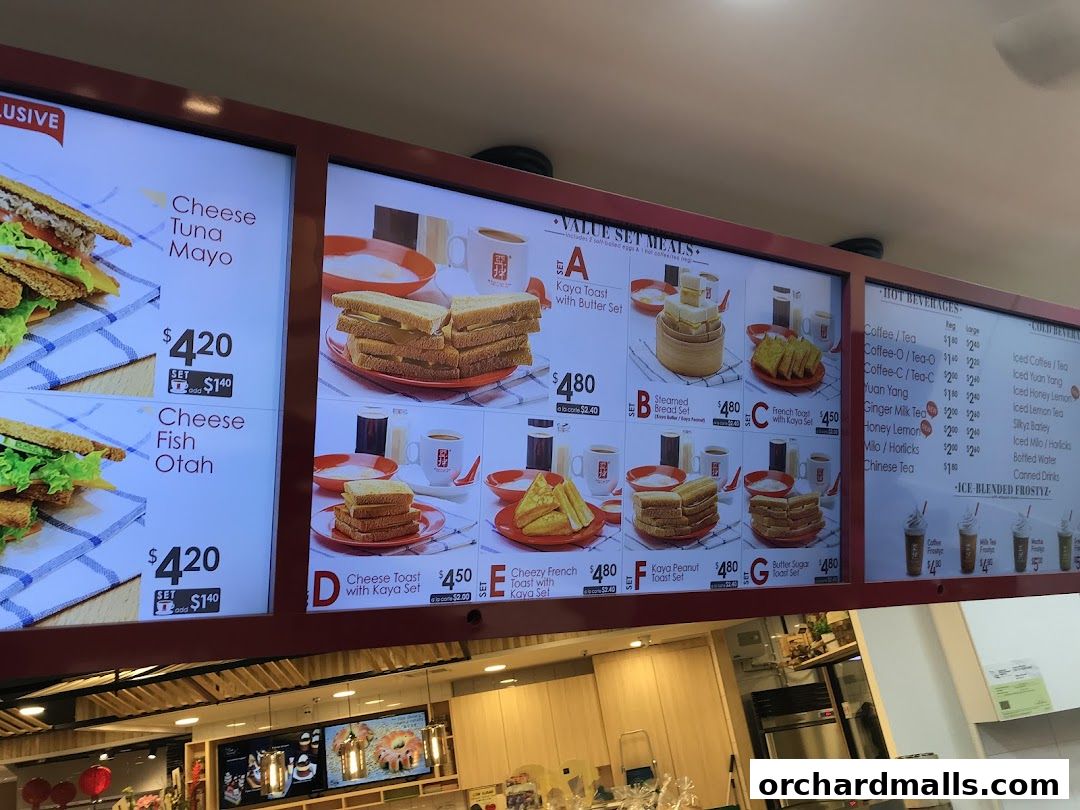 A digital menu board displaying various toast sets, sandwiches, and beverages at Ya Kun Kaya Toast.
