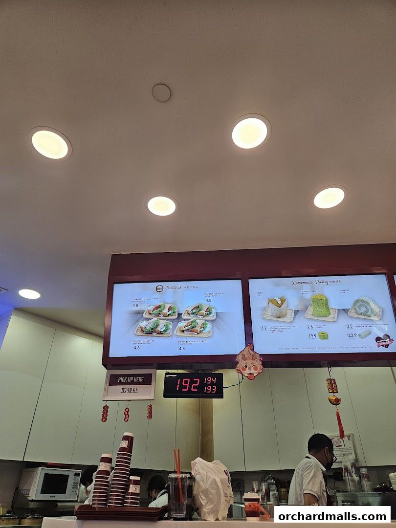 A counter display at Ya Kun Kaya Toast shows menu items and a digital queue number.