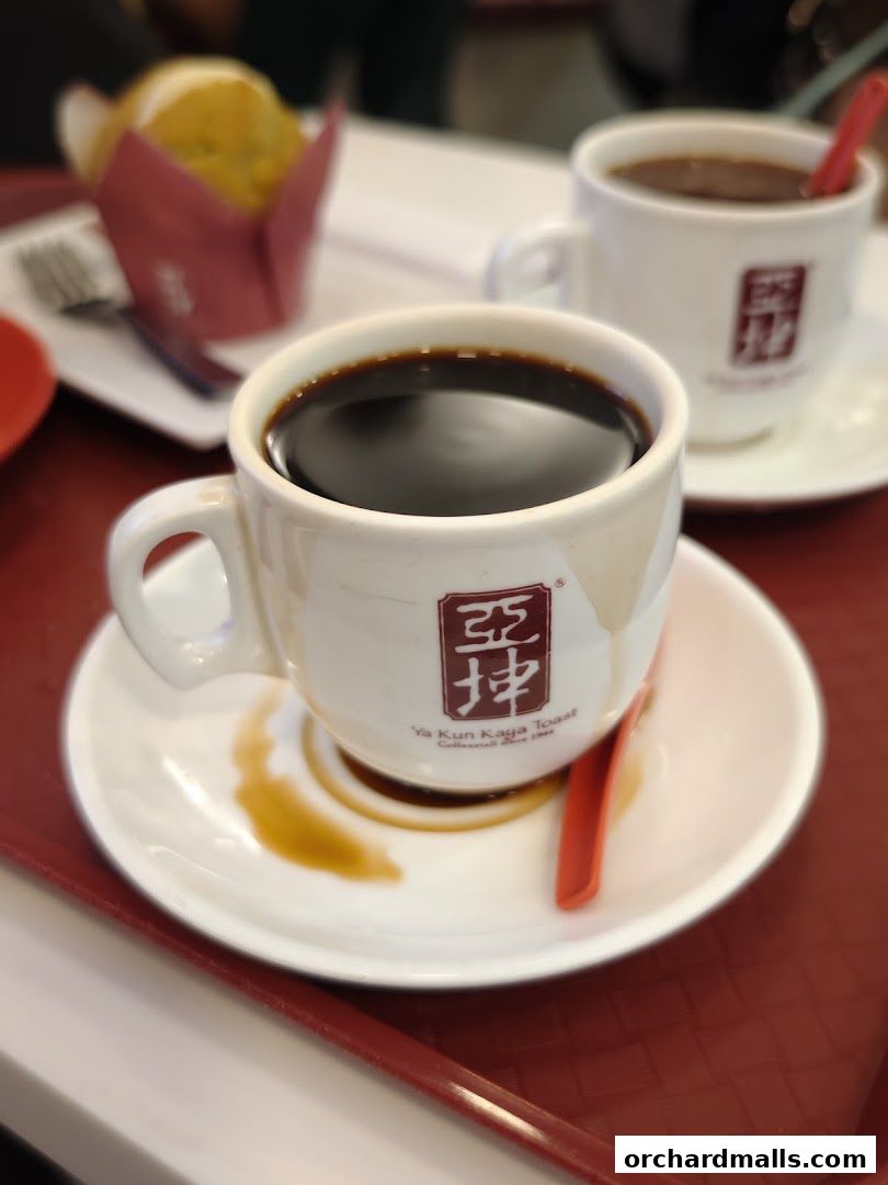 Two cups of coffee and a muffin on a red tray at Ya Kun Kaya Toast.