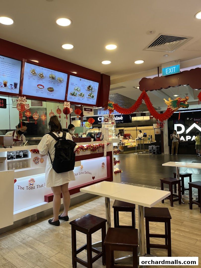A customer orders at Ya Kun Kaya Toast, with menus displayed and festive decorations.