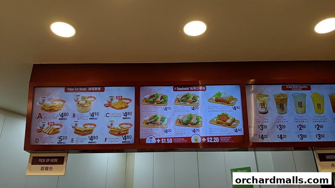 A digital menu board displaying various set meals, toastwiches, and drinks at Ya Kun Kaya Toast.
