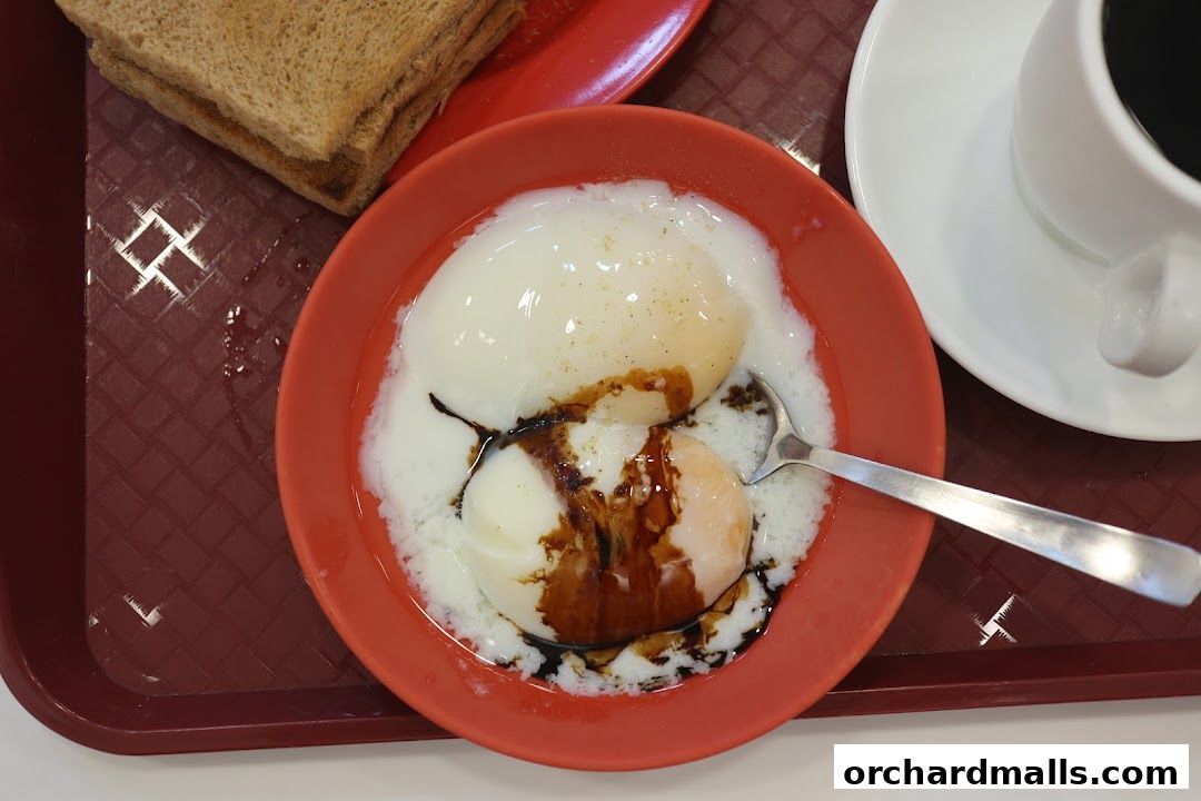 A close-up of soft-boiled eggs with soy sauce and pepper, served with toast and coffee.