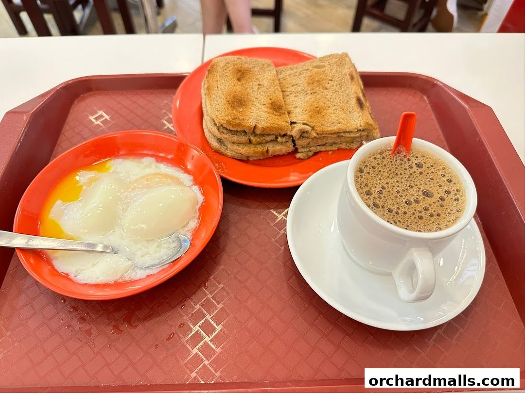 A tray with soft-boiled eggs, kaya toast, and a cup of coffee.