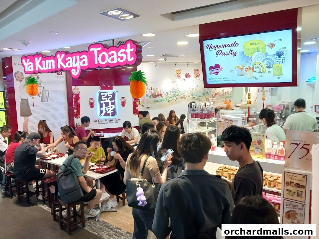 Customers dine at Ya Kun Kaya Toast, with a display of homemade pastries and merchandise visible.