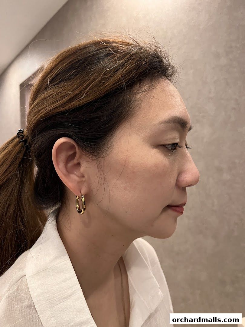 A woman with brown hair and hoop earrings, wearing a white shirt.