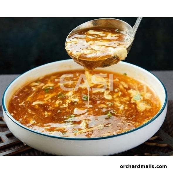 A ladle pours steaming hot and sour soup into a white bowl.