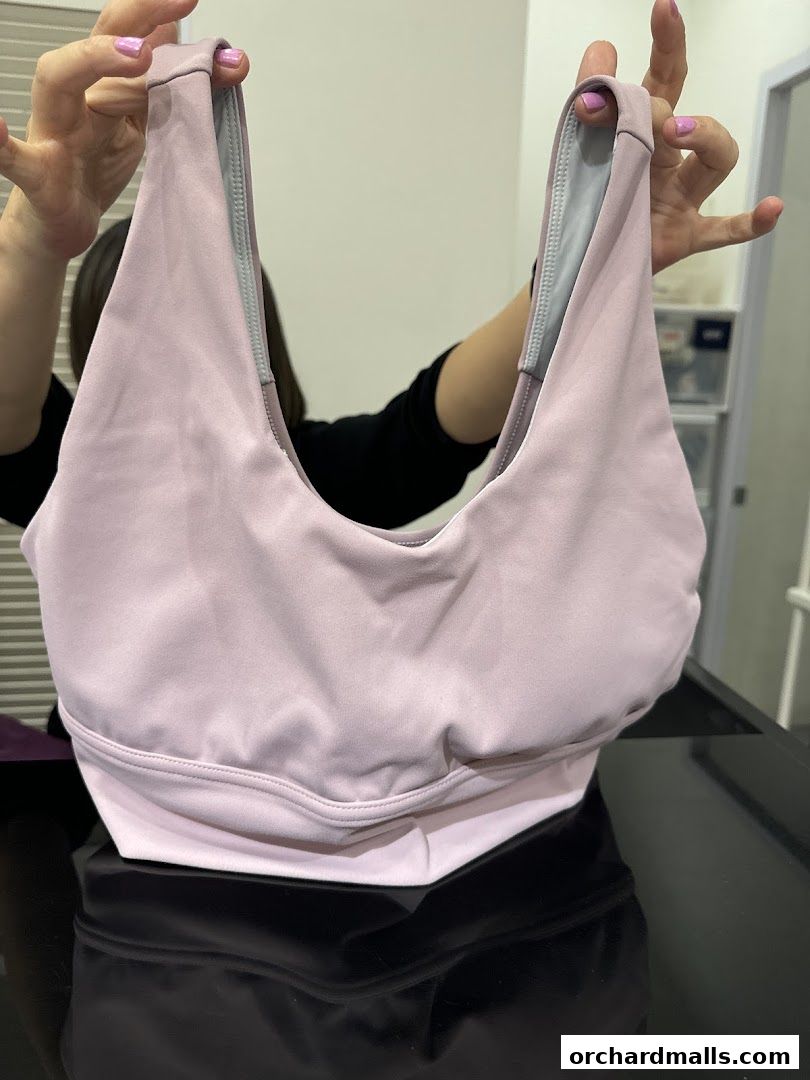 A person holds up a light purple sports bra with grey lining.