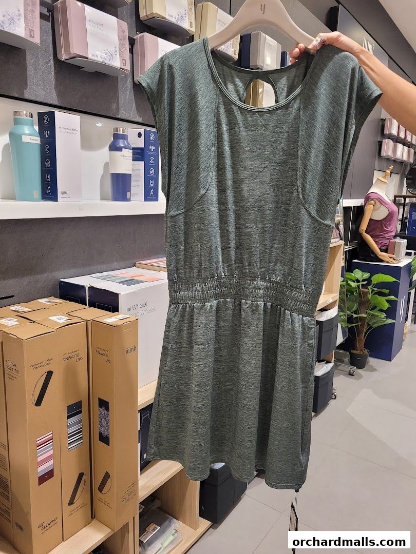 A person holds up a green athletic dress in a retail store.