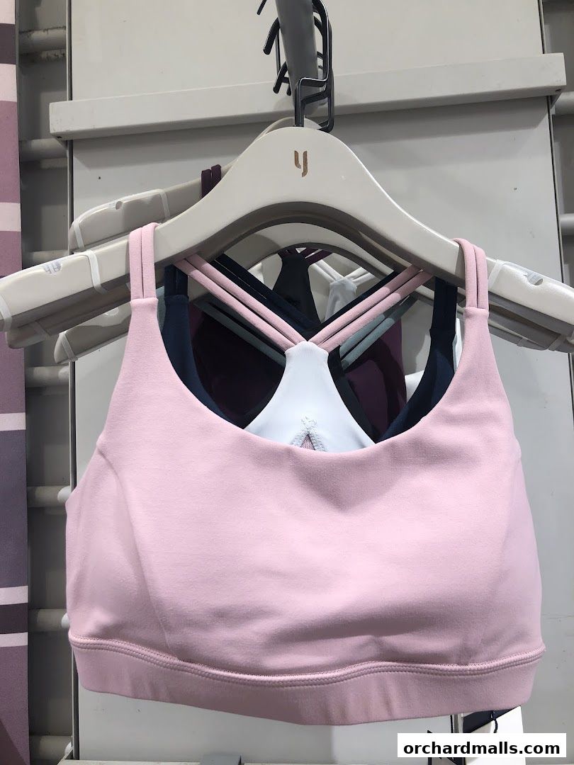 A rack of colorful sports bras with the Yumi Active logo on the hangers.