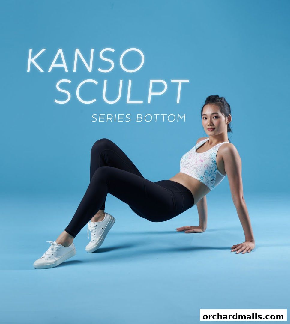 A woman in activewear poses on a blue background, promoting the Kanso Sculpt Series Bottom.