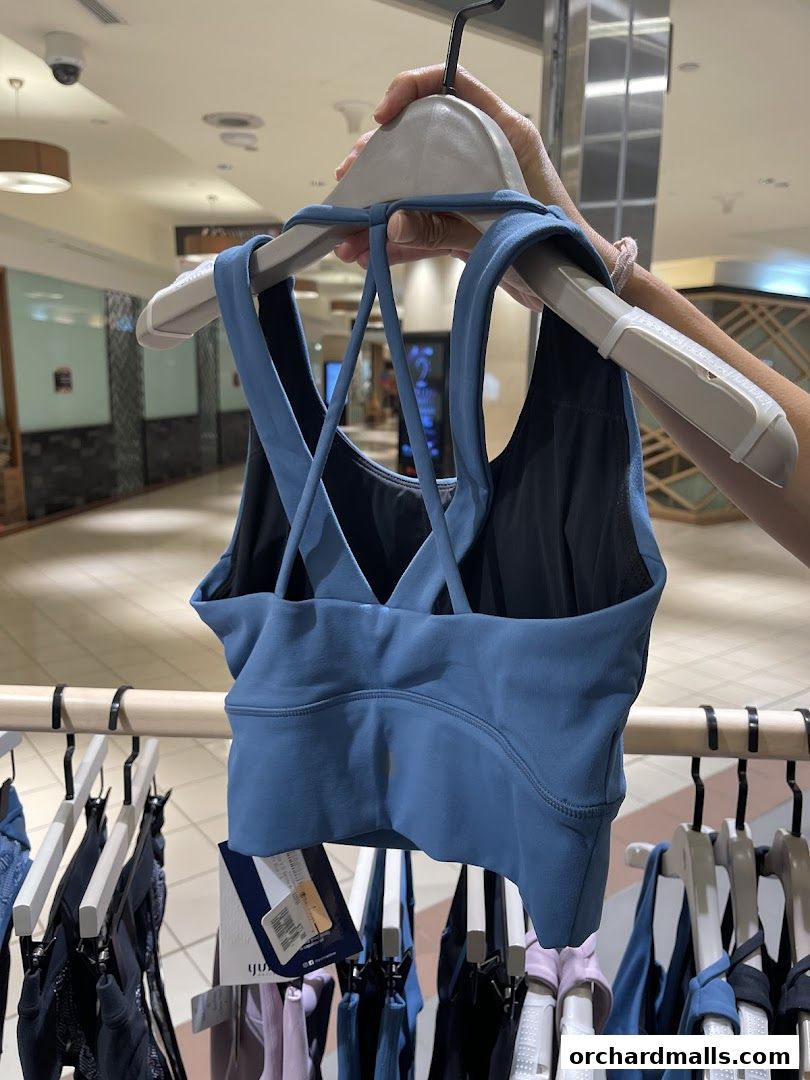 A person holds up a blue sports bra from Yumi Active in a retail store.