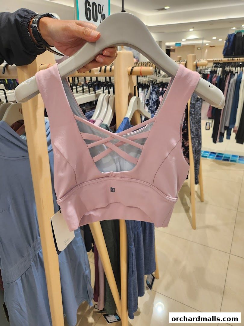 A pink sports bra with a criss-cross back detail is displayed on a hanger.