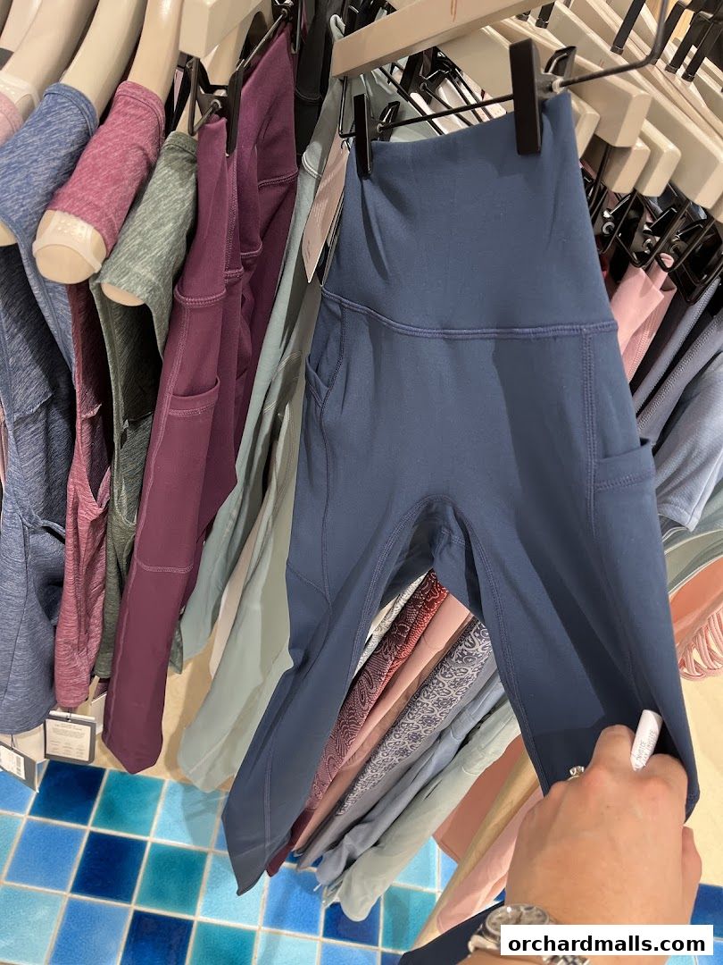 A selection of activewear leggings in various colors and styles hanging on a rack.