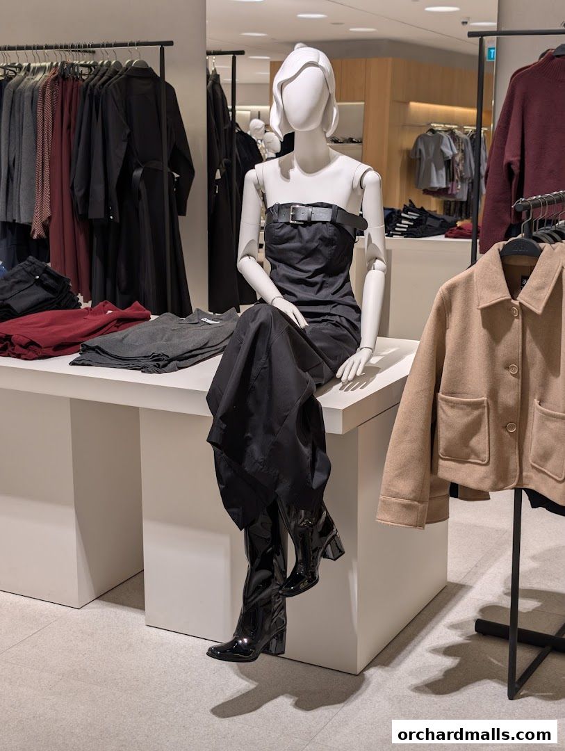 A mannequin displays a black strapless dress and boots in a clothing store.