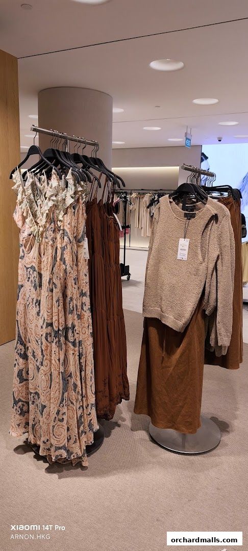 A display of women's dresses and a sweater with skirts in earthy tones.