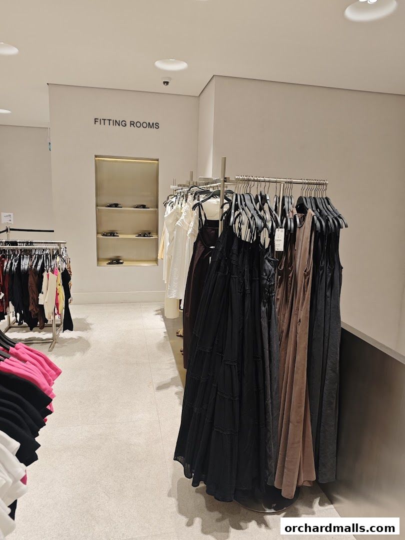 Interior view of a Zara store with racks of clothing and a sign for fitting rooms.