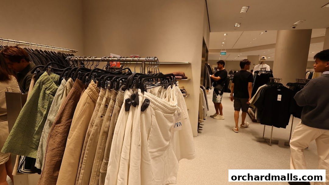 Interior view of a Zara clothing store with racks of apparel and shoppers browsing.