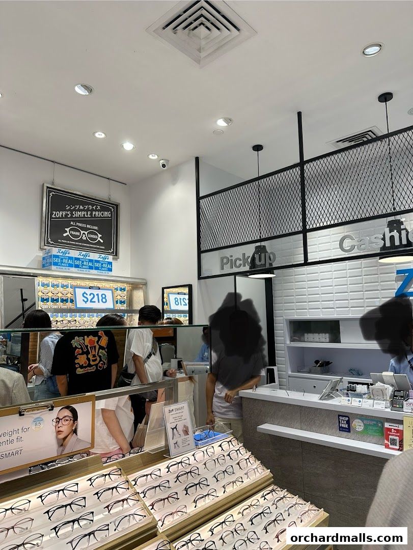 Interior of an optical shop with displays of eyeglasses and customers at the counter.