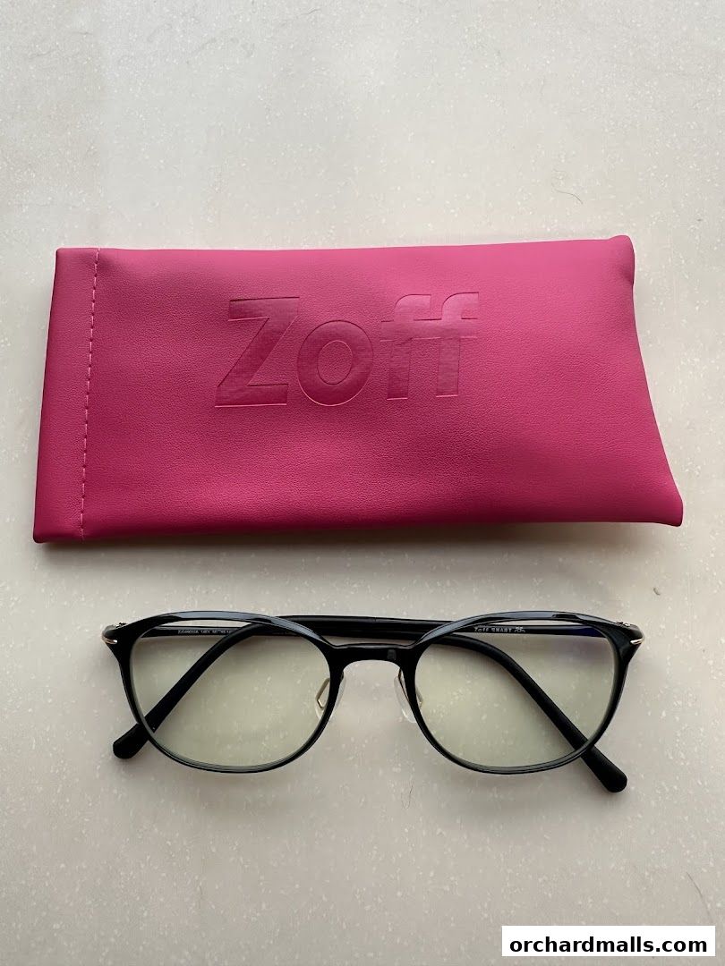 A pair of black Zoff eyeglasses with a pink Zoff branded glasses case.